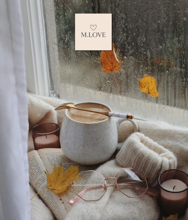 Chávena de café e livro junto à janela num dia de chuva — imagem aconchegante de outono para o blog M.Love sobre autocuidado.