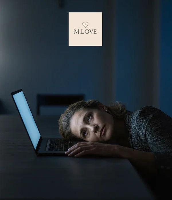 Mulher cansada apoiada em laptop aberto em ambiente escuro, expressão pensativa e logo M.LOVE ao fundo
